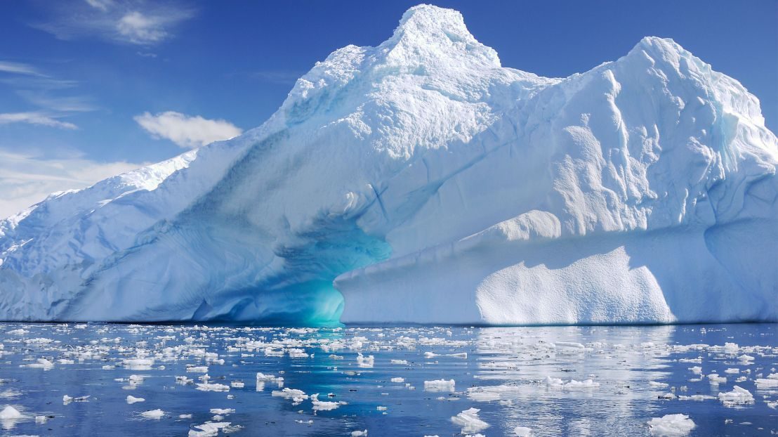 A tabular iceberg with a blue ice arch, floating in brash ice off the Antarctic Peninsula